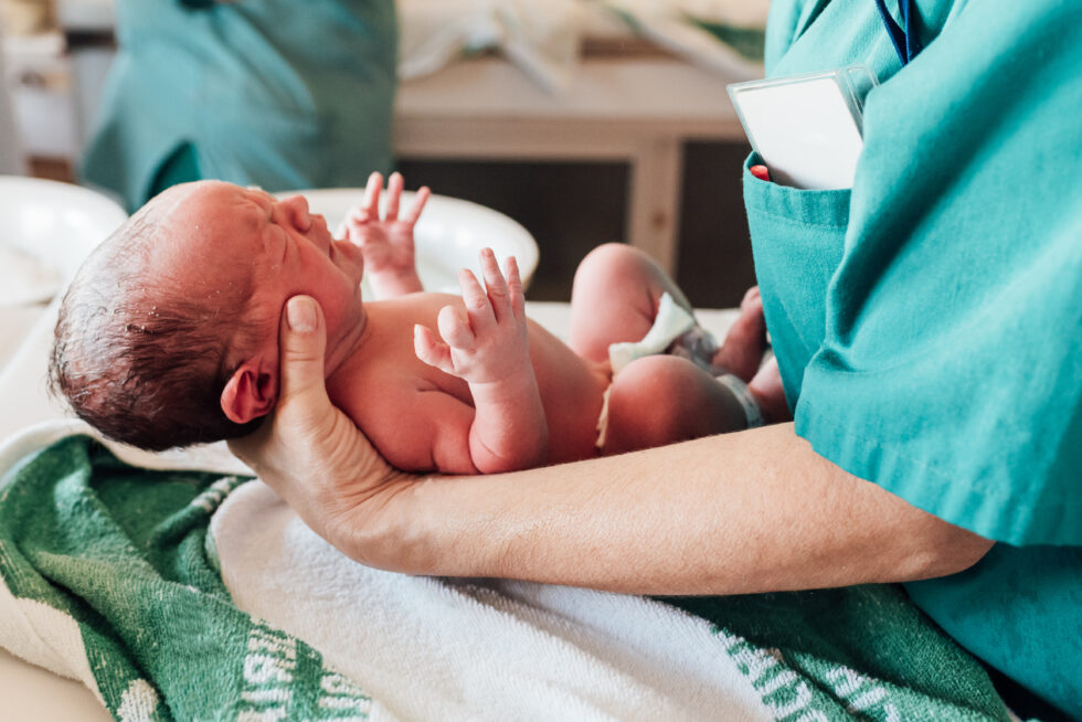 baby held by person in hospital